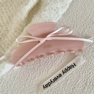 Detail of pink acetate hair claw with delicate ribbon bow and gold lettering