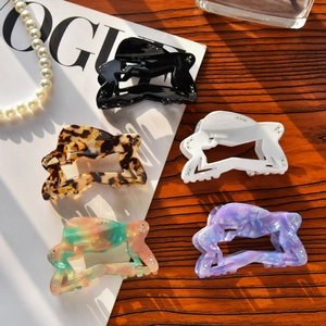 Set of five hollow star acetate hair claws with rhinestones on a wooden desk with pearls