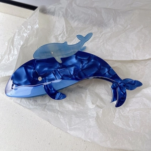 Détail macro d'une grande pince à cheveux baleine en acétate bleu avec yeux en strass