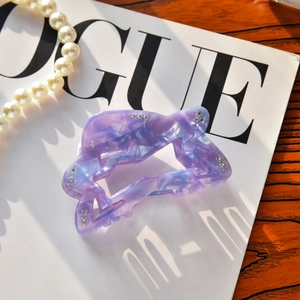 Detailed view of purple marble acetate star hair claw clip with rhinestones on Vogue magazine