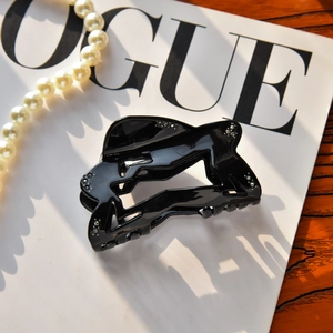 Detail of glossy black hollow-out hair claw clip with rhinestones on a Vogue magazine