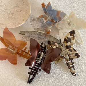 Elegant acetate butterfly hair claws in various marble patterns with golden metal springs