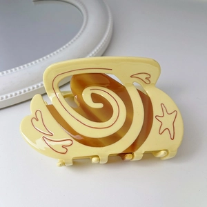 Detail of yellow acetate hair claw with red heart and star patterns on white background