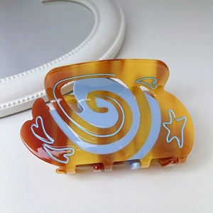 Detail of tortoise shell acetate claw clip with blue spiral, star and heart patterns