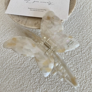 Close-up of cream white butterfly hair claw clip with marble texture and metal spring