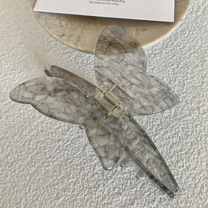 Macro shot of butterfly wing hair claw with grey marble pattern and golden spring detail