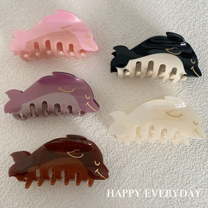 Dolphin shaped acetate hair claws set in pink, white, and amber with polished finish