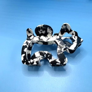 Close-up of hollow dog-shaped hair claw clip with black and white marble acetate texture