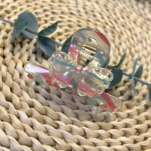 Pince à cheveux papillon en acétate rose et bleu avec ressort doré sur tapis tressé