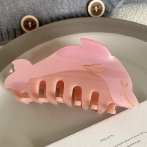 Detailed view of a pink dolphin-shaped hair claw clip with elegant gold outlines and a sleek finish