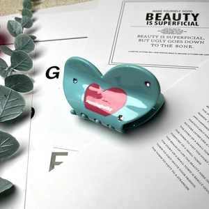 Blue acetate heart hair claw clip with rhinestones and floral accents on white card