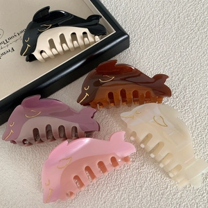 Acetic acid dolphin hair claws in five colors on a beige fabric background with prop