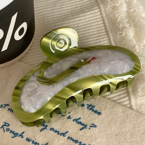 Detailed close-up of a green acetate hair claw clip with marble texture and snake design