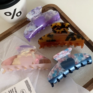 Close-up of heart-shaped acetate hair claws in purple, tortoiseshell, and pink marble patterns