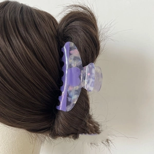 Detailed view of a purple marble acetate heart hair claw clip on a hairstyle