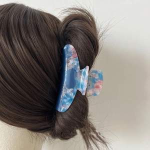 Detail of blue and pink marble acetate hair claw clip worn in a stylish updo hairstyle