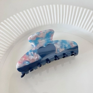 Close-up of heart acetate hair claw with marble texture on a white ceramic plate