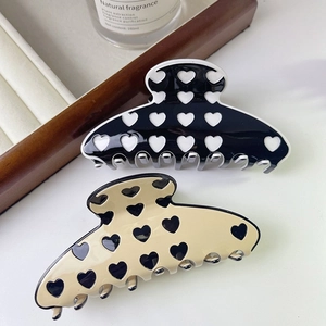 Close-up of acetic acid hair claws with heart patterns in black and beige finishes