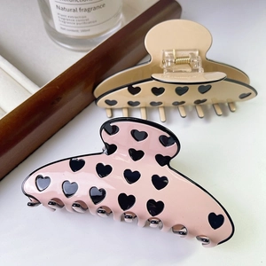 Detail of pink and beige heart pattern hair claws with metallic spring mechanisms