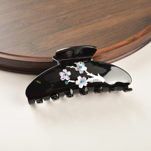 Détail d'une pince à cheveux noire avec fleurs violettes et strass bleus