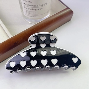 Macro shot of large black and white heart patterned acetate claw clip on wood background