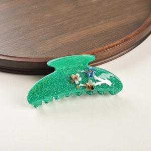 Détail macro de la pince à cheveux vert émeraude avec paillettes dorées et motifs floraux