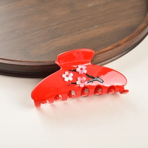 Détail de la pince à cheveux rouge en acétate avec fleurs de prunier et strass incrustés