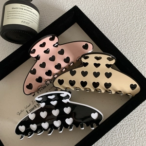 Three acetate hair claws set with heart pattern in pink, beige and black finish