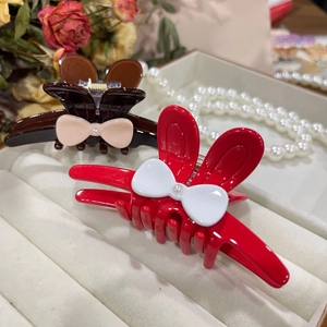 Elegant rabbit ear hair claw clips with acetate bows and pearl accents on white velvet