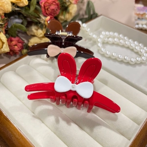 Close-up of rabbit ear hair claw clips with bows and pearls on a white velvet tray