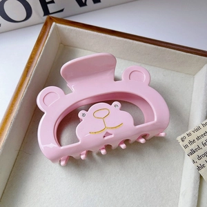 Détail de la pince à cheveux ours rose avec contours dorés et petits strass brillants