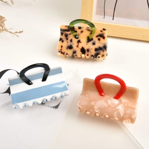 Three creative acetate handbag-shaped hair claws in marble and tortoiseshell patterns
