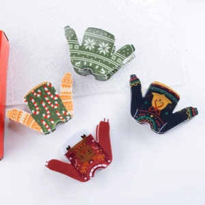 Détail de quatre pinces à cheveux en acrylique motif pull de Noël avec cloches festives