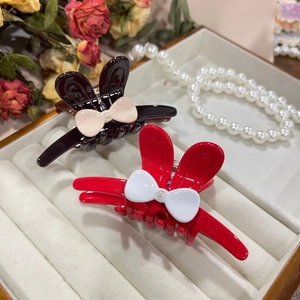 Close-up of rabbit ear hair clips with pearl bows in black and red on velvet box