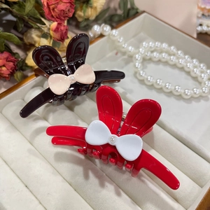 Elegant rabbit ear claw clips with bow and pearl accents on white leather display box