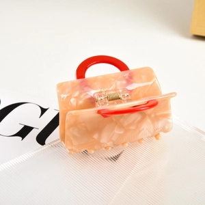 Detailed macro view of the peach marble acetate hair claw with a mini handbag design