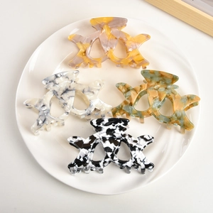 Set of four hollow acetate hair claws in marble and spotted patterns on a white plate