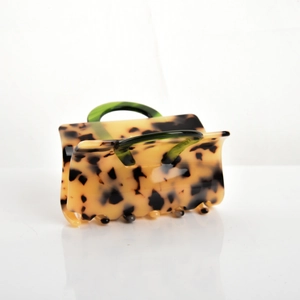 Detail of yellow tortoiseshell hair claw clip with green handle on white background