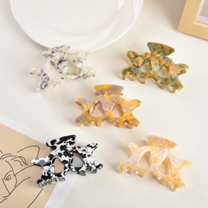 Detailed macro view of five large acetate hair claws with premium marble and amber textures