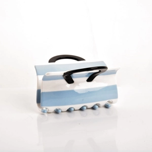 Detail view of a blue and white striped acetate hair claw clip with black handles