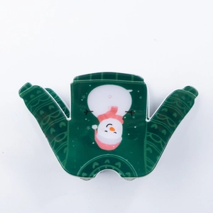 Détail d'une pince à cheveux verte en forme de pull avec motif bonhomme de neige Noël