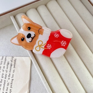 Detail of Christmas claw clip with Corgi dog in festive red sock on velvet box