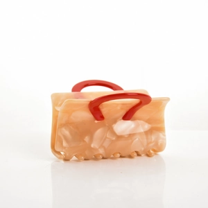Detail of square acetate hair claw clip featuring marble pattern and red handle design