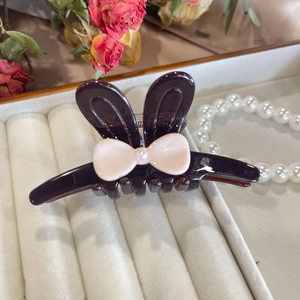 Detail of bunny ear hair claw with acetate finish, pearl bow, and shark clip teeth