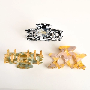 Detailed view of three acetate hair claws in marble, tortoise, and gradient patterns