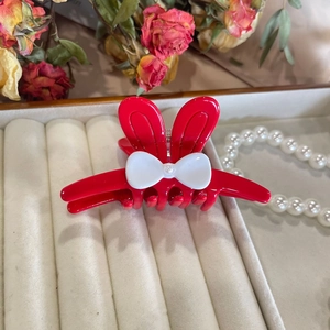 Detailed view of red rabbit ear hair claw with white bow on luxury jewelry display box