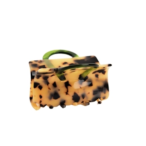 Tortoiseshell acetate hair claw clip with green handles in handbag shape on white background