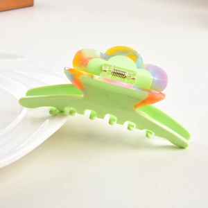 Detail view of large green acetate hair claw clip with colorful cloud patterns and metal spring