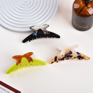 Three acetate bow hair claws in tortoiseshell and solid colors on a luxury textured base