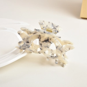 Detail of hollow acetate hair claw clip with black and white marble texture and gold spring